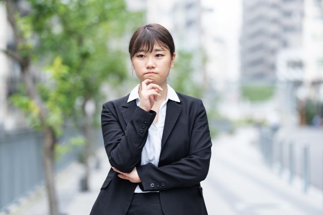 悩むスーツの女性